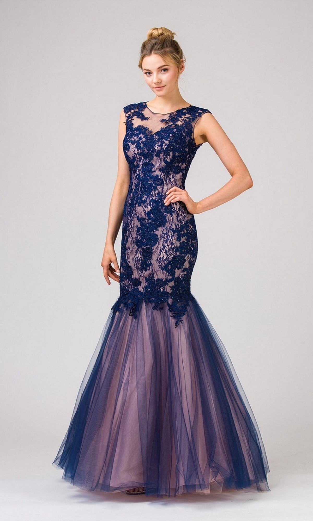 A woman poses against a light background wearing the Eureka 8510 long prom dress in Navy/Blush, featuring a sleeveless lace bodice, open back, and sheer tulle mermaid skirt.